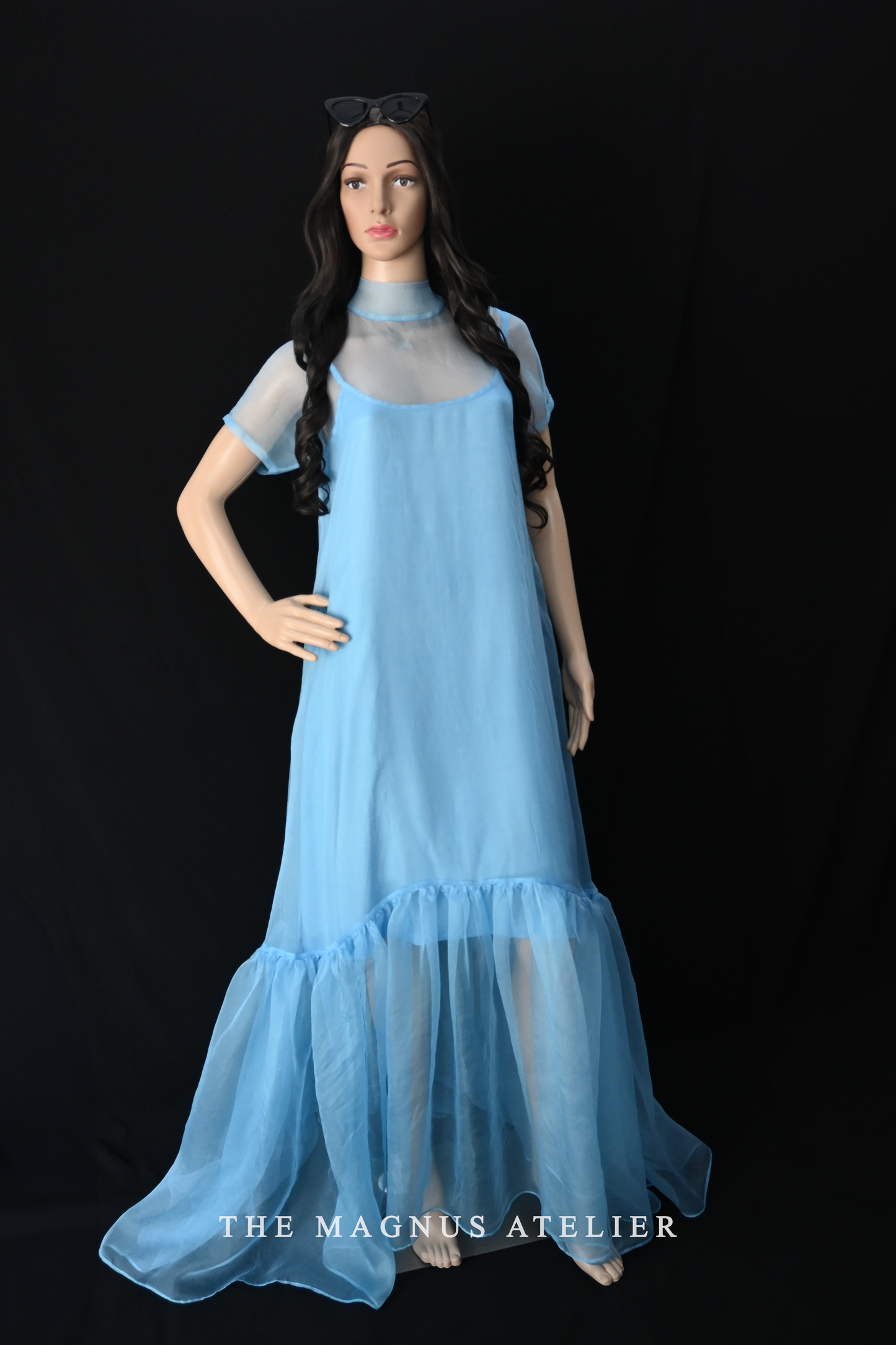 Mannequin wearing sheer sky blue layered organza dress with ruffled hem, transparent long designer dress for women