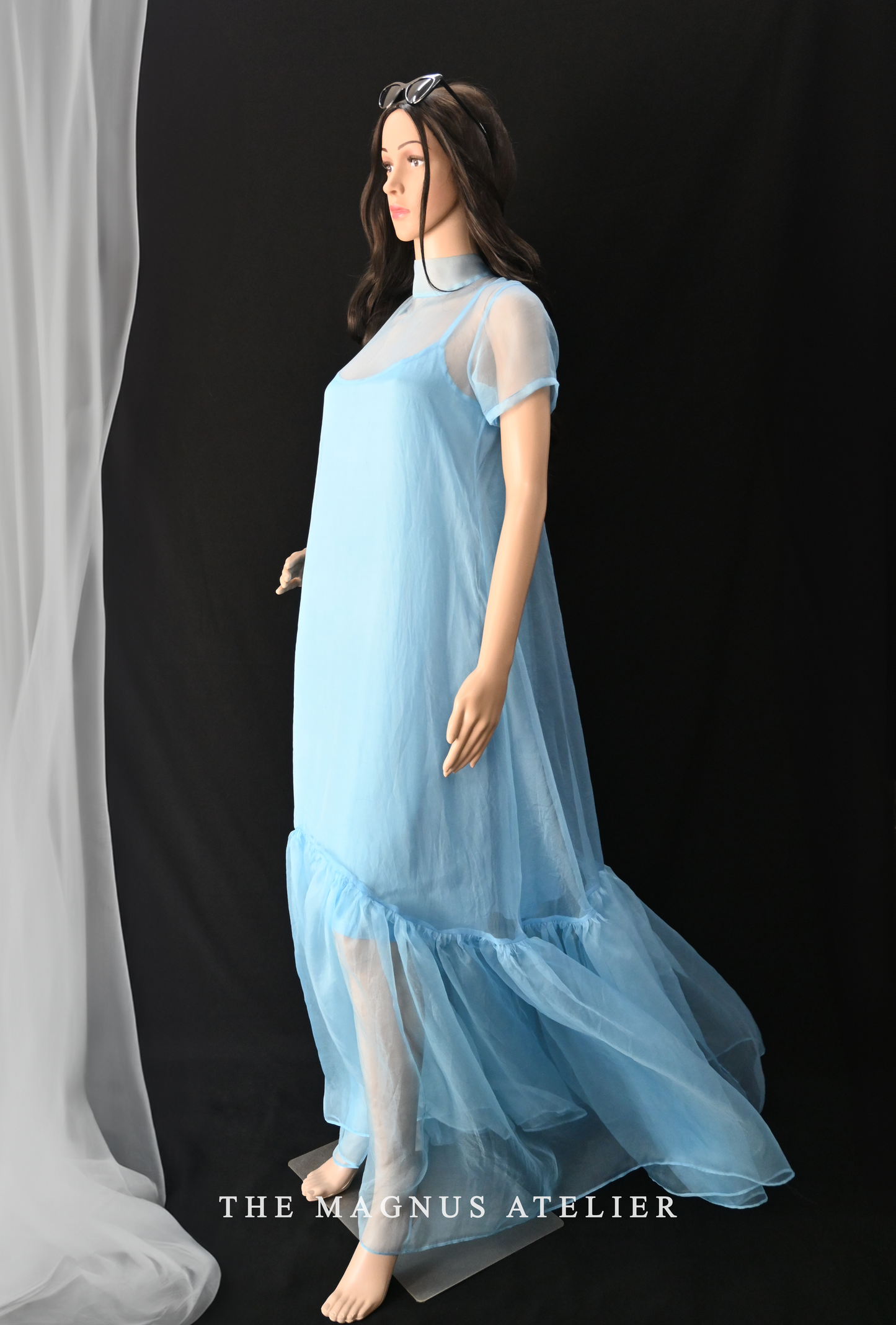 Mannequin wearing layered organza dress with ruffled hem, transparent long designer dress for women
